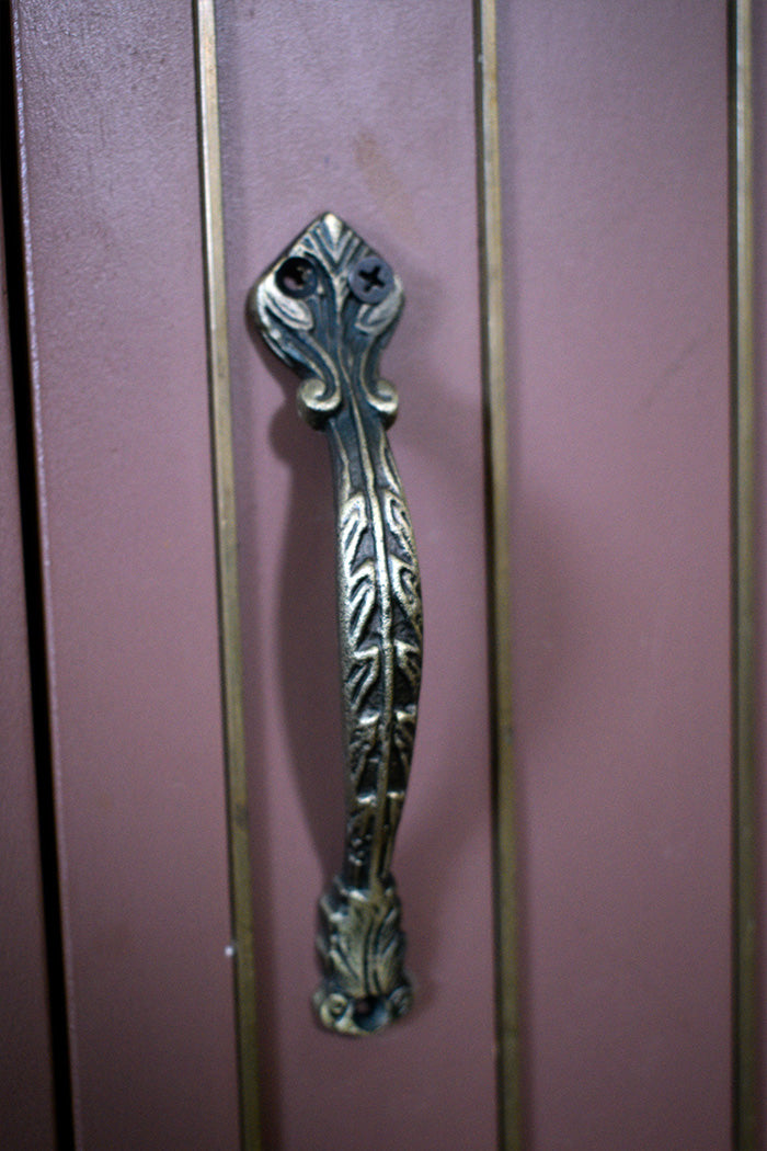 Decorative metal handle on a pinkish-brown surface