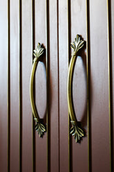 Pair of zinc handles on a wooden cabinet