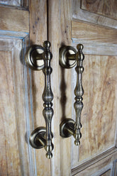 Pair of ornate zinc handles on a wooden cabinet door