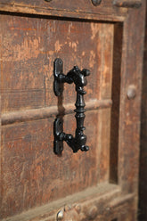 Close-up of a black metal handle on a wooden door