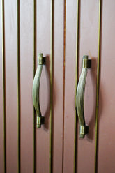 Two zinc cabinet handles on a wooden cabinet