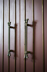 Decorative zic handles on a wooden door with vertical slats.