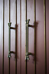 Decorative zic handles on a wooden door with vertical slats.
