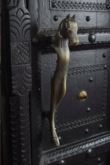 Decorative metal door handle shaped like a horse head on an ornate black door.