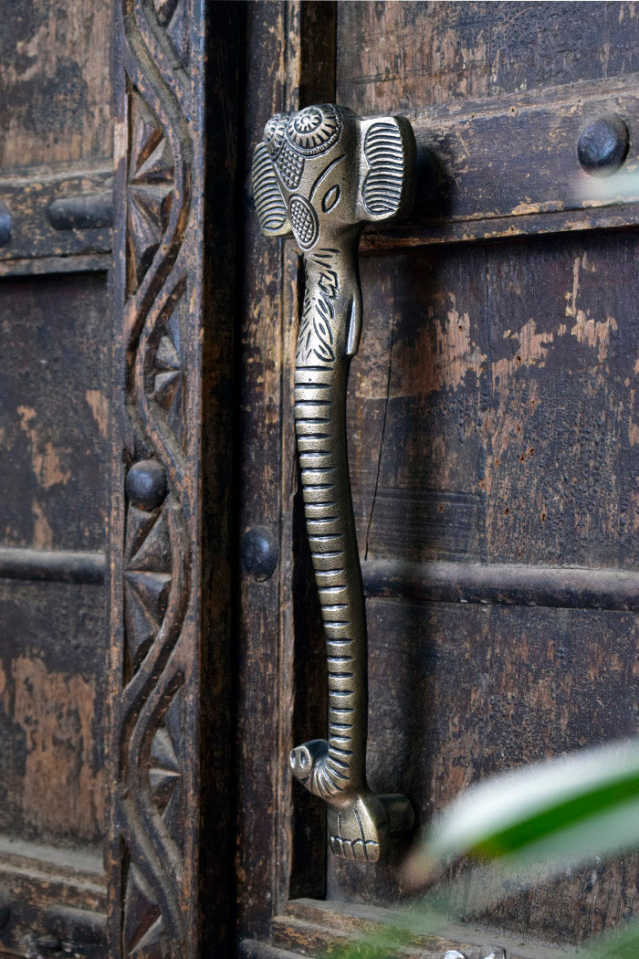 Decorative iron ganesha door handle on an ornate wooden door