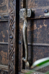 Decorative iron ganesha door handle on an ornate wooden door