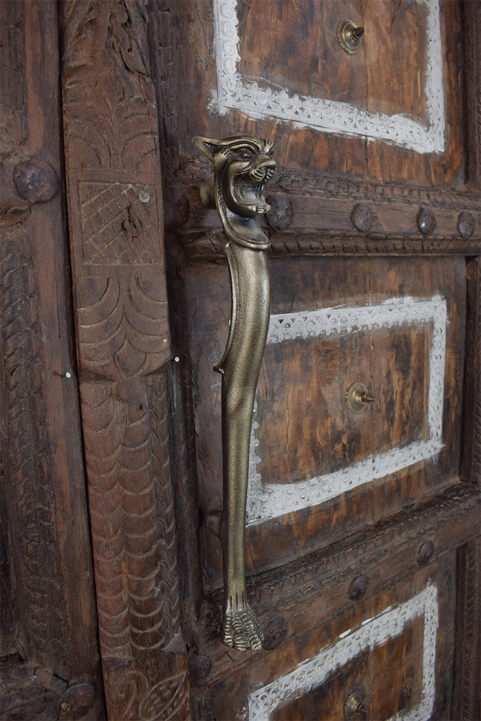 Decorative wooden door with a iron door handle featuring a lion design.