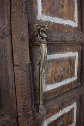 Decorative wooden door with a iron door handle featuring a lion design.