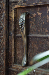 Decorative iron metal handle with lion head design on a wooden door