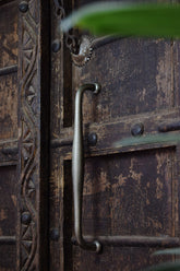 Close-up of a rustic wooden door with metal handle and decorative patterns