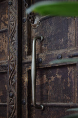 Close-up of a rustic wooden door with metal handle and decorative patterns