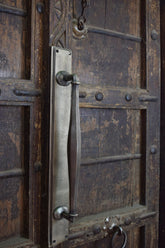 Close-up of a metallic door handle on an aged wooden door