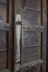 Close-up of a metallic door handle on an aged wooden door