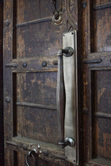 Metal door handle on a rustic wooden door