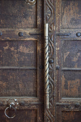 Close-up of an ornate wooden door with metal handle and decorative carvings.