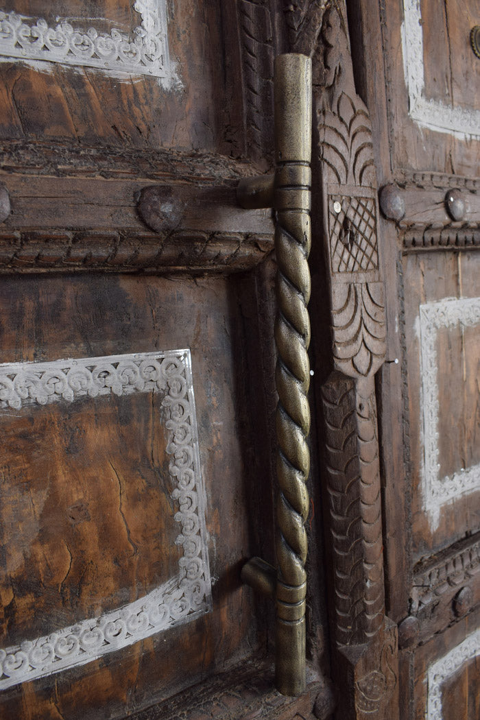 Decorative wooden door with intricate carvings and a iron handle.