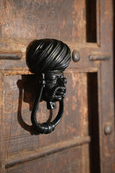 Iron door knocker with a face of Rajasthani man on a wooden door
