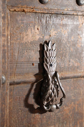 Decorative pineapple metal door knocker on a wooden door