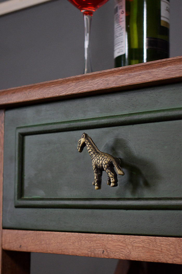 Green drawer with a giraffe-shaped handle, wine glass, and bottle in the background.