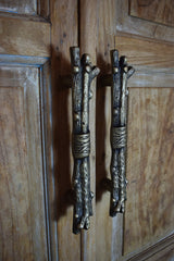Pair of decorative iron cabinet handles on a wooden door.