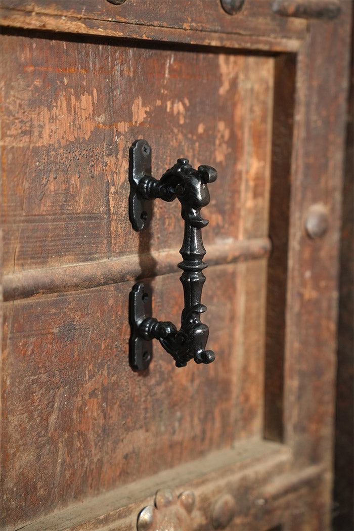 Close-up of a black metal handle on a wooden door