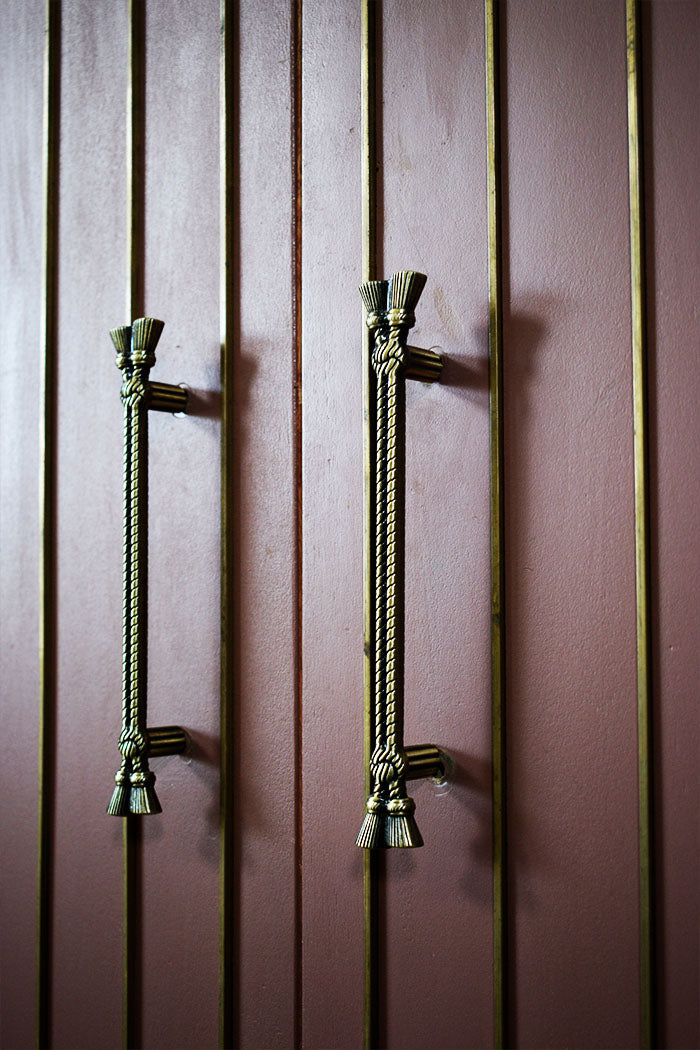 Decorative zic handles on a wooden door with vertical slats.