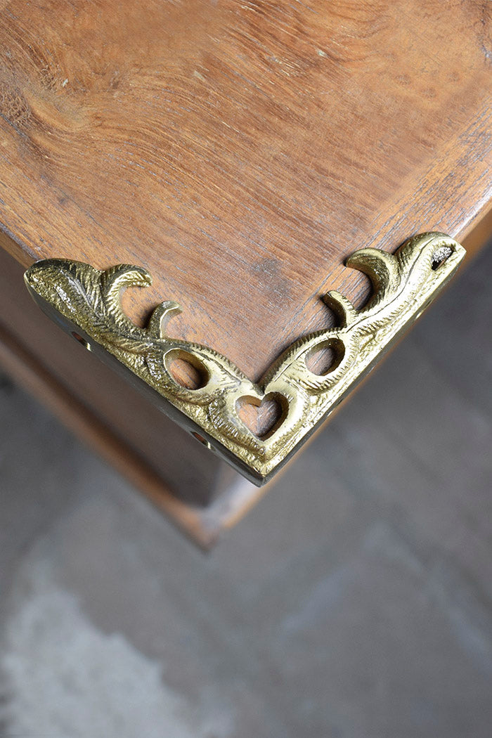 Decorative brass corner bracket on a wooden surface