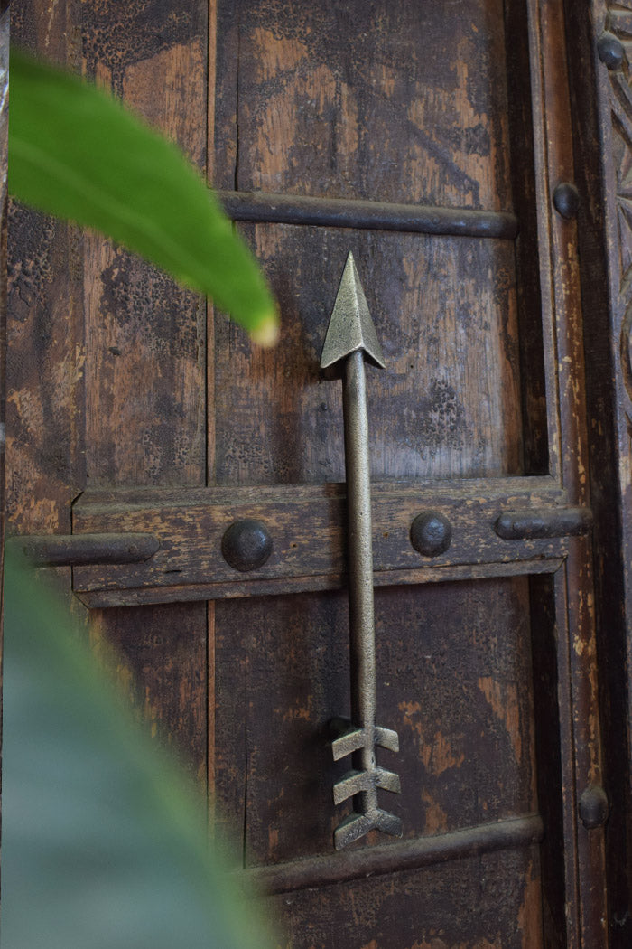 Decorative metal arrow door handle on a wooden door 