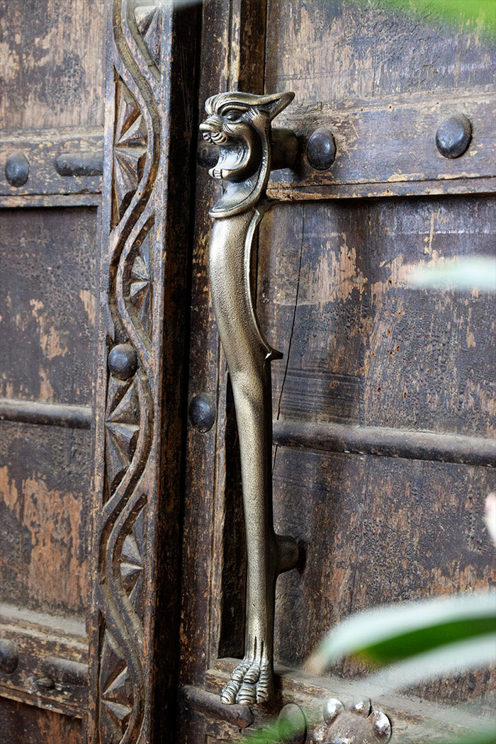 Decorative iron metal handle on a wooden door with intricate lion carvings