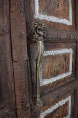 Decorative wooden door with a iron  door handle featuring a lion design.