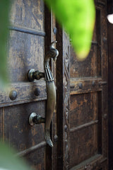 an ornate wooden door with a peacock metal handle