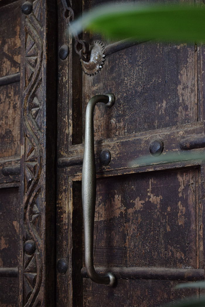 Close-up of a rustic wooden door with metal handle and decorative patterns