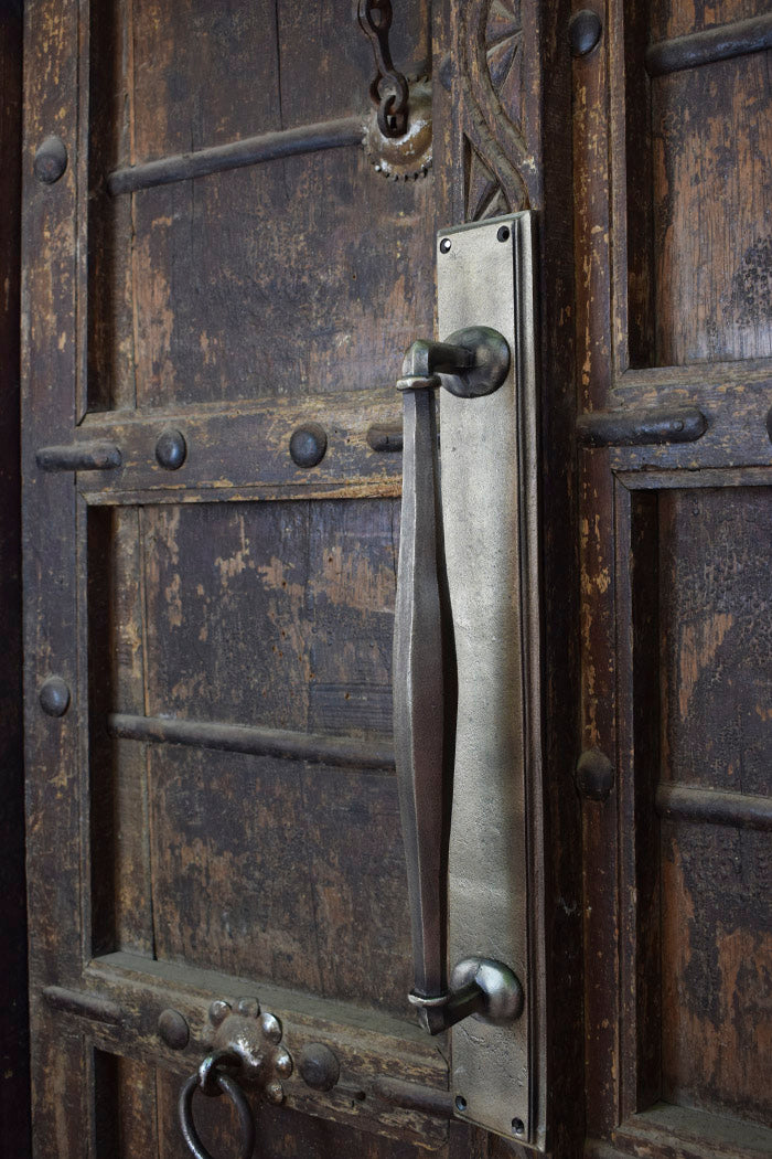 Metal door handle on a rustic wooden door