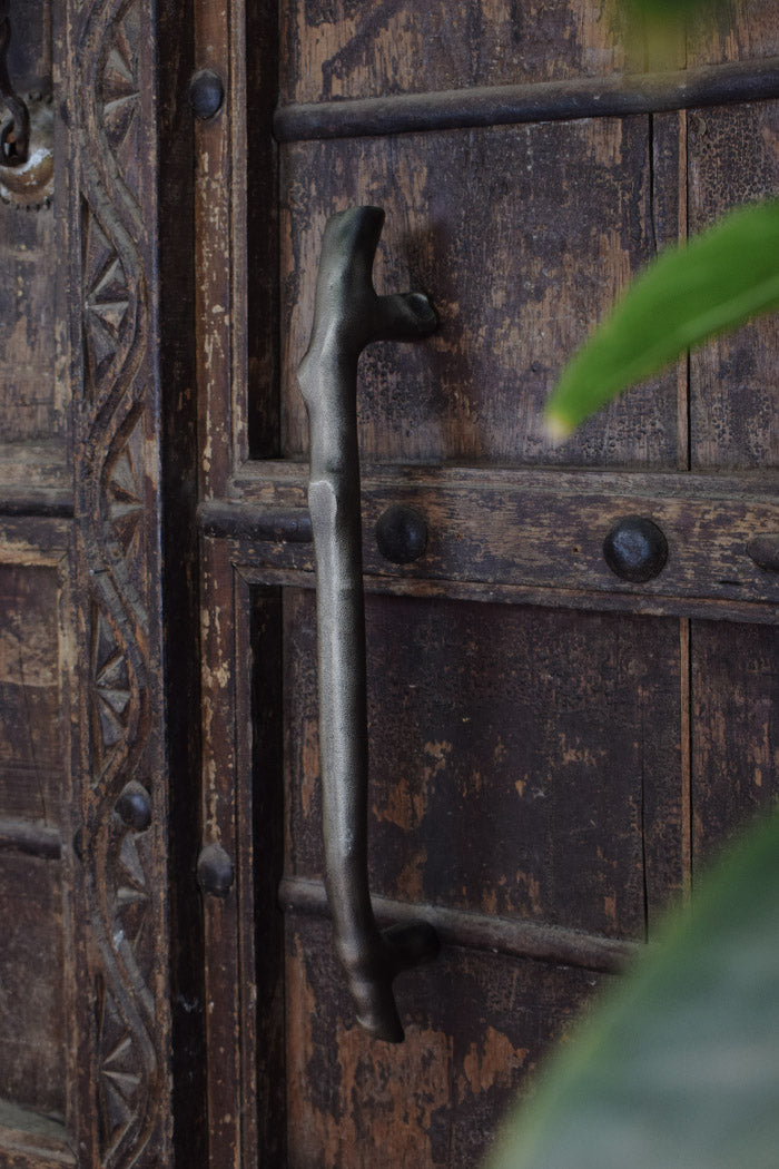 Close-up of an ornate wooden door with a metal handle and decorative carvings.