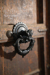 Decorative iron door knocker on a wooden door
